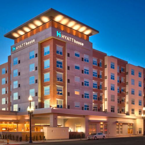 This image shows the exterior of a Hyatt House hotel building during twilight, featuring illuminated signage and multiple floors of guest rooms.