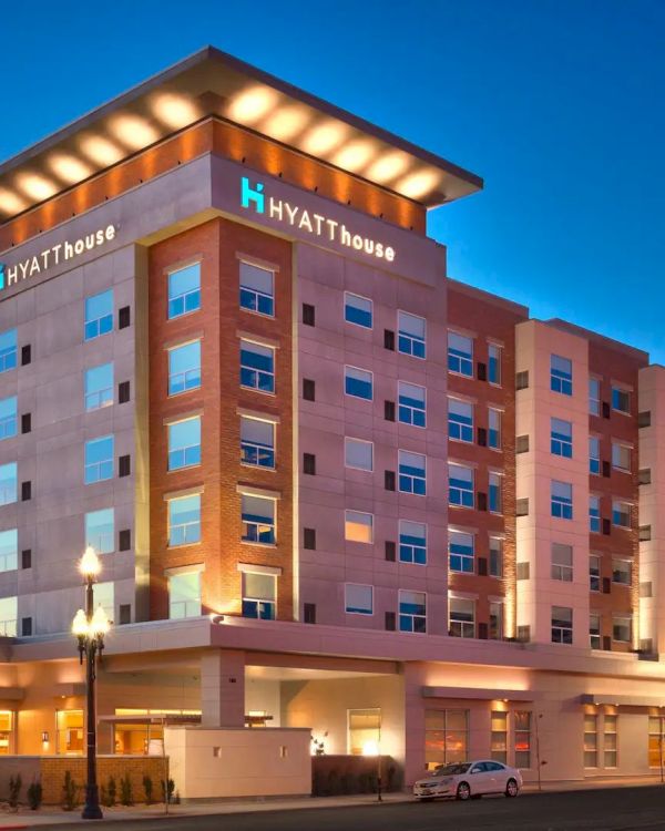 This image shows the exterior of a Hyatt House hotel building during twilight, featuring illuminated signage and multiple floors of guest rooms.