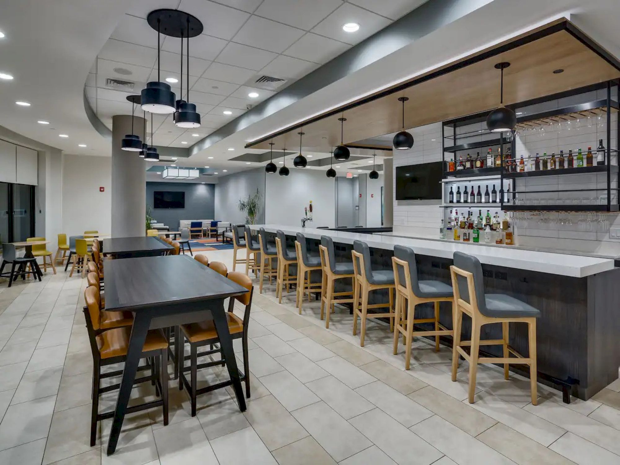 A modern bar with high stools, hanging lights, and bottles displayed on shelves; sleek and inviting atmosphere.